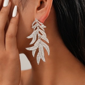 Détail de boucles d'oreilles feuilles en argent avec cristaux portées par un mannequin
