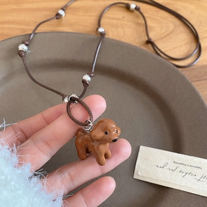 Vue détaillée d'un pendentif caniche marron émaillé sur un collier en cordon tressé
