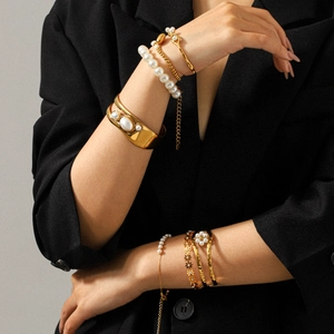 Détails de bracelets en perles dorées et joncs minimalistes portés par un modèle féminin