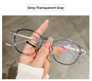 Detailed view of transparent grey eyeglass frames with slim metal temples held by hand