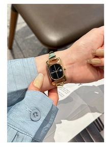 Close-up of elegant women's square gold watch with black dial and metal chain strap