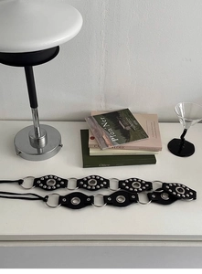 Detail of Y2K punk belt featuring black leather discs and silver metal rings and studs