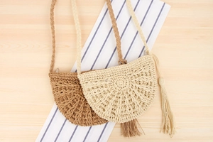 Detail of handmade bohemian straw crossbody bag with long tassels and crochet patterns