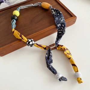 Detailed close-up of Bohemian necklace with floral fabric strips and diverse artisan beads