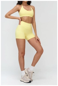 Close-up of yellow yoga set showing ribbed fabric texture and cross-back sports bra design
