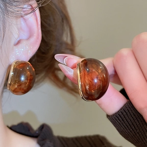 Close-up of amber resin earrings with gold trim and textured vintage Maillard style