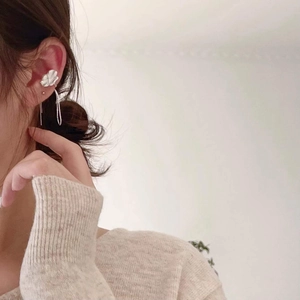 Close-up of S925 sterling silver flower ear cuff with tassel drop on model ear