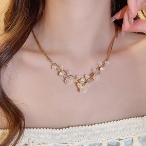 Close-up of golden multi-layer necklace with pearl accents and resin flower pendants