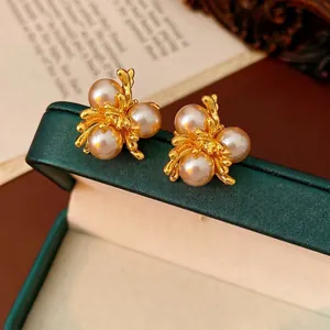 French vintage gold flower earrings with pink pearls on a green jewelry box