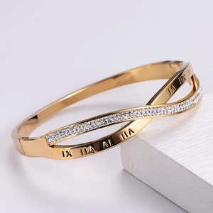 Close-up of gold crossover bracelet with Roman numeral engraving and pavé set crystals
