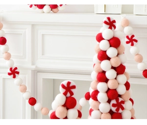 Handmade wool felt ball garland and mini Christmas trees on a white mantel fireplace