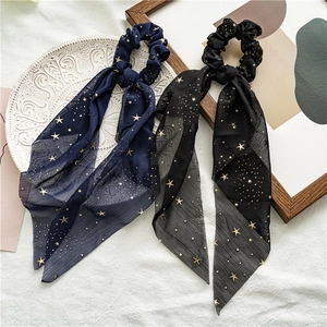 Detail of navy and black chiffon scrunchies with gold stars on white textured fabric