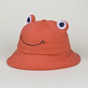Detail of orange cotton frog sun hat showing 3D eyes and embroidered smiley face