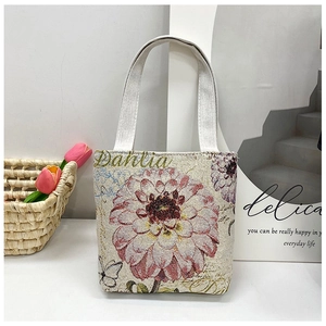 Detail of floral canvas tote bag featuring pink Dahlia embroidery and cozy home setting