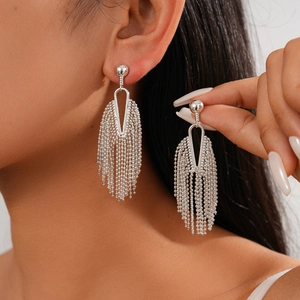 Silver tassel drop earrings with geometric chain links worn by a fashion model