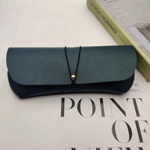 Dark green leather sunglasses case with lychee texture and gold bead closure detail