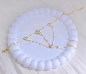 Detailed macro view of gold-plated finger bracelet with pearl and flower charm