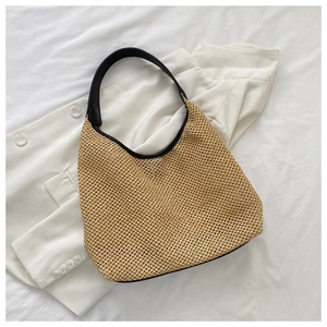 Detail view of woven straw tote with black leather straps on aesthetic resort background