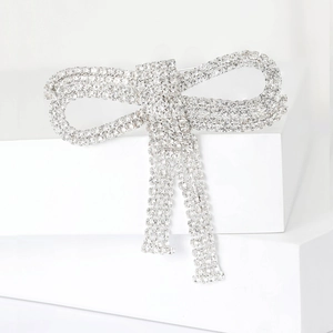 Detailed view of silver-toned bowknot brooch with full rhinestones on white steps