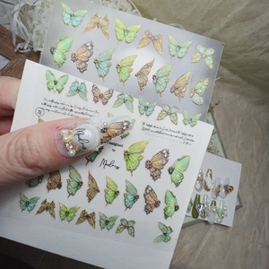 Macro shot of 3D embossed butterfly nail art stickers in mint green and pale gold