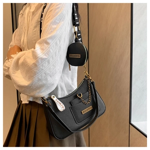 Detail of black pebbled leather handbag with wide logo strap and round coin purse pouch