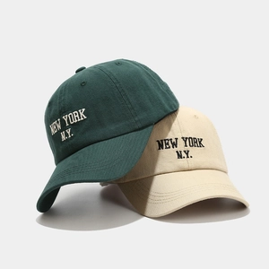 Green and beige cotton baseball caps with New York embroidery in a minimal studio shot