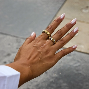 Detail of waterproof 18K gold and silver stainless steel twisted rings on a hand