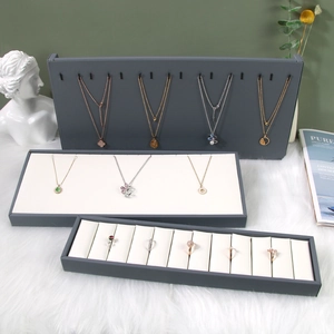 Premium dark grey and beige jewelry display set for necklaces and rings on plush carpet