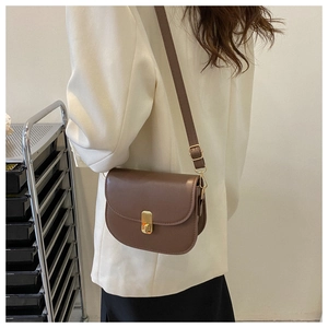 Detailed back view of a brown vintage saddle bag worn by a model with golden buckle detail