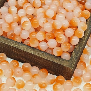 Macro shot of 10mm gradient orange and pink glass beads in a wooden bowl for DIY jewelry