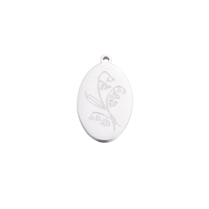 Macro shot of lily of the valley engraving on a silver oval stainless steel pendant
