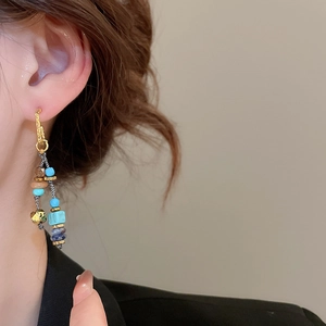 Dettaglio ravvicinato di orecchini pendenti boho chic indossati da una modella in posa