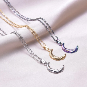Three minimalist crescent moon pendants on silk, gold and silver hammered textures