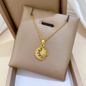 Close-up of gold star and moon pendant with sparkling crystals in a beige jewelry box