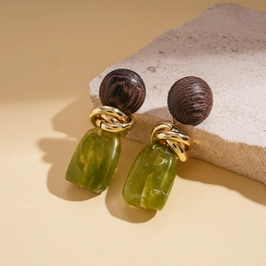 Detail view of retro earrings with dark wood beads, gold metal, and green resin charms