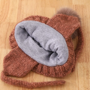 Caramel knit children's winter hat with warm earflaps and a fluffy brown pompom