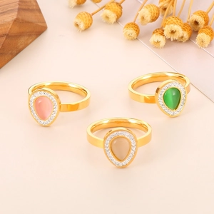 Detailed macro view of gold-plated teardrop rings featuring cat-eye stones and rhinestones