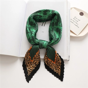 Green floral and leopard print pleated silk scarf displayed on an open book page