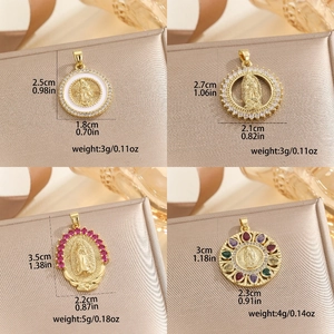 Golden Virgin Mary pendants with colorful cubic zirconia and dimensions displayed on fabric