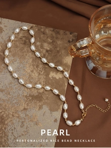 Detail view of natural white rice pearl necklace with gold beads and extender chain