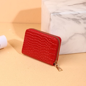 Red crocodile texture accordion card wallet with gold zipper on marble stone