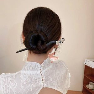 Detail of wooden flower hair pin styled in a bun with delicate white floral accents