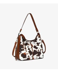 Detail of fashion cow print tote bag showing leather strap and metal hardware accents
