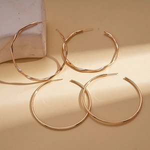 Minimalist geometric round twisted gold stud earrings with smooth and textured finishes