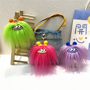Close-up of colorful monster plush keychains with cartoon eyes on a denim bag