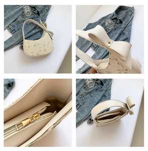 Detail of floral embroidery and bow knot on beige woven faux straw crescent bag