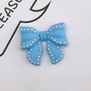 Detail of sky blue resin bow accessory with faux pearl trim for DIY crafts and jewelry