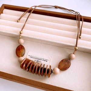 Detail of amber resin discs and cream beads on a leather bohemian necklace cord