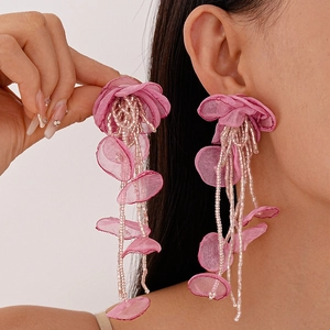 Detailed close-up of pink handmade lace flower earrings with beaded long fringe on model