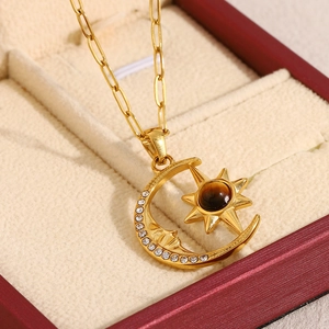 Close-up of 18K gold plated celestial necklace with moon and sun charms on velvet